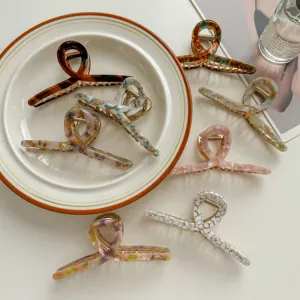 Detail shot of elegant acetate hair claws featuring unique marbled patterns and metallic teeth.