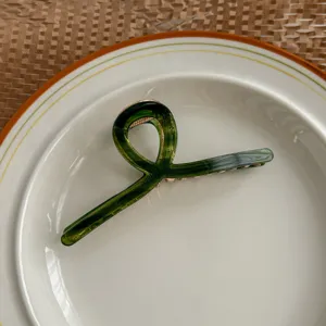 Detailed close-up of a dark green translucent acetate hair claw clip, elegant design for styling.