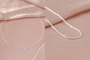 Close-up detail van de glinsterende zilveren ketting op een elegante roze satijnen achtergrond.