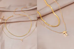 Gedetailleerde close-up van de elegante dubbellaagse gouden ketting met een fijn kruis hangertje.