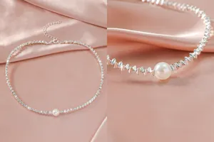 Detailopname van een sprankelende zilveren ketting met een delicate parel op roze satijn.