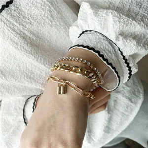 Primo piano dettagliato di un set bracciali multipli dorati stile punk con strass e lucchetto.