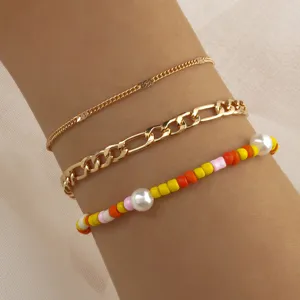 Detailed close-up of a 3-piece gold chain and colorful seed bead pearl bracelet set.