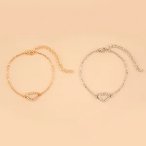 Vue détaillée de bracelets charmes cœur exquis en or et argent avec des strass étincelants.
