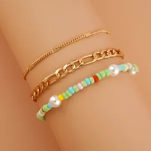 Detail shot of a 3-piece layered bracelet set featuring gold chains and colorful pearl beads.