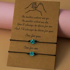 Close-up detail of matching braided cord bracelets with blue glitter beads on a kraft card.