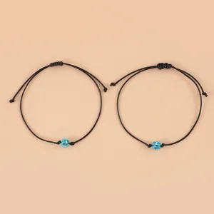 Closeup detail of black braided cord bracelet featuring glowing blue bead for daily wear.