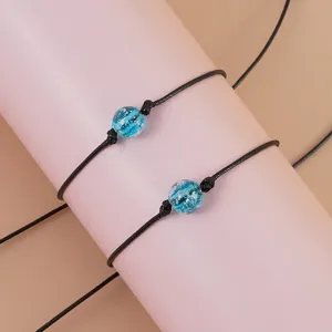 Close-up of black woven cord bracelets featuring luminous blue beads, adjustable design details.