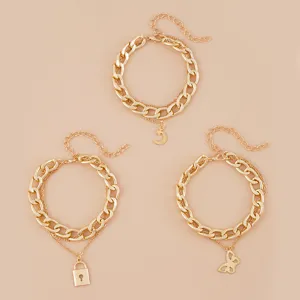 Dettagli in primo piano di bracciali a catena dorata multistrato con luna, lucchetto e farfalla.