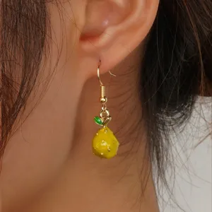 Primo piano dettagliato del grazioso orecchino a frutto giallo indossato, design chic.