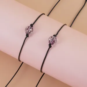 Detail view of black braided rope bracelet featuring luminous beads with adjustable design.