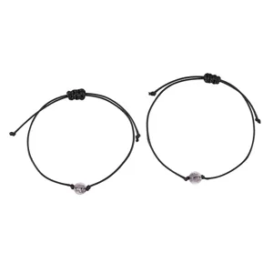 Detailed view of the black braided rope bracelet with a luminous glowing bead and adjustable cord.