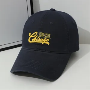 Navy blue baseball cap detail showing yellow Chicago embroidery and soft cotton fabric.