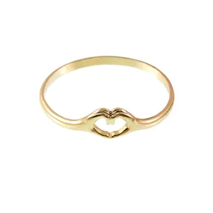 Gros plan de la bague en métal doré présentant un délicat motif de mains formant un cœur.
