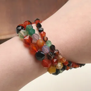 Vue détaillée de bracelets de perles en pierres précieuses facettées sur le poignet.