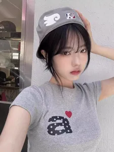 Casquette de baseball grise style coréen avec patch d'aile blanche et t-shirt gris.