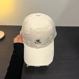 Gorra de béisbol beige desgastada para mujer con bordado de letras y estilo casual urbano.
