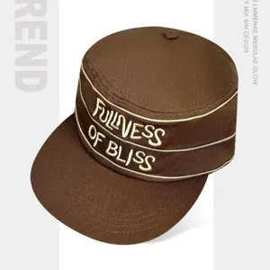 Gorra plana marrón estilo coreano con letras bordadas y ala ancha de estilo streetwear urbano.