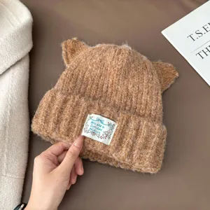 Gros plan détaillé du bonnet chaud en tricot marron avec oreilles de chat et étiquette.
