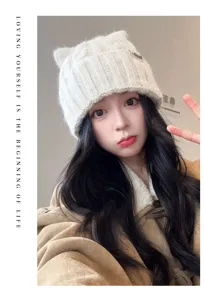 Close-up detail of cute knitted cat ear beanie in cream white, cozy winter warm hat.
