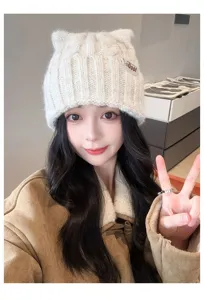 Close-up detail of a cute cat ear knit beanie in off-white, cozy wool winter hat for women.