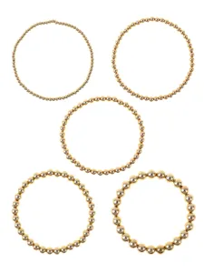 Dettaglio di bracciali elastici con perline dorate in varie dimensioni ideali per stile quotidiano.