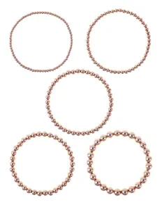 Dettaglio in primo piano di bracciali elasticizzati con perline dorate in varie misure.
