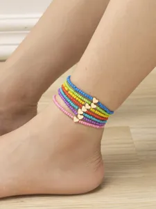 Cavigliera con perline di vetro multicolore e ciondoli a cuore dorati in dettaglio