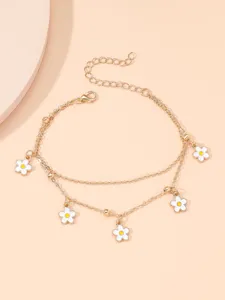 Close up detail of a dainty double layer gold anklet with white enamel flower charms.