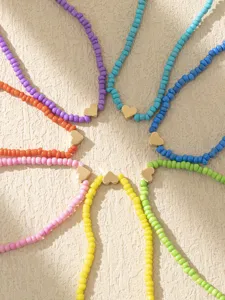 Dettaglio ravvicinato di cavigliere con perline di vetro colorate e cuore dorato