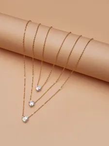 Detailed view of layered gold-tone necklace featuring sparkling heart-shaped zirconia pendants.