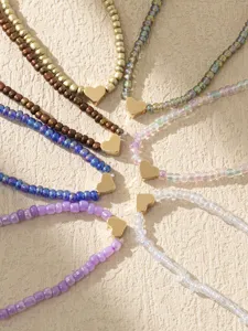 Primo piano dettagliato di cavigliere boho in perline di vetro con graziosi cuori dorati.