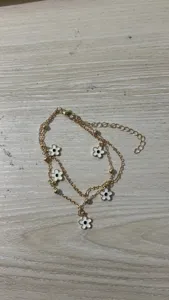 Double layer gold chain anklet featuring cute white enamel flower charms and delicate beads.