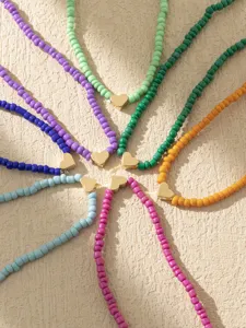 Cavigliera perline vetro colorate boho con ciondolo cuore oro, dettaglio gioiello piede donna.