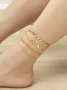 Close-up detail of a stylish multi-layer gold anklet set featuring a sparkly snake pendant.