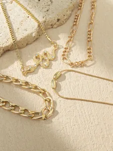 Gold layered necklace set featuring a sparkling rhinestone snake pendant and various chic chains.