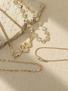 Detailed view of fashionable gold snake pendant necklace and layered chain jewelry set.