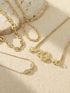 Gold-tone layered chain anklet set featuring sparkling rhinestone snake pendant design.