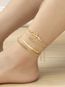 Detailed view of the layered gold anklet set featuring a sparkly rhinestone snake pendant.