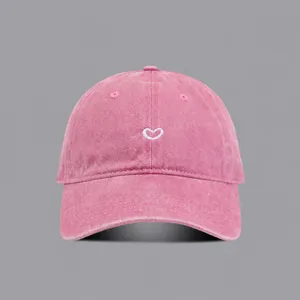 Detail view of the vintage washed pink baseball hat featuring a cute white heart embroidery.