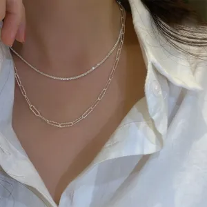 Close-up detail of a double layer silver necklace, sparkly chain and paperclip link design.
