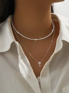 Close-up detail shot of a sparkling double layer silver necklace with a delicate cross pendant.