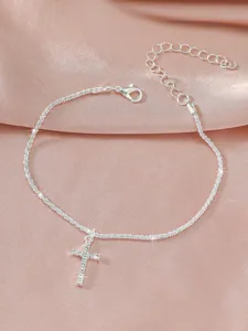Detailaufnahme der silbernen Kreuz-Fußkette mit funkelnden Steinen und feiner Gliederkette.
