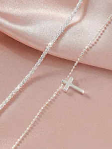 Wunderschöne silberne Kreuz Fußkette mit glitzerndem Ketten Design auf rosa Satin.