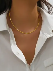 Detail shot of a delicate sparkling gold chain necklace worn on the neck for daily elegance.