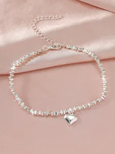 Silberfarbene Perlchen-Fußkette mit Herz-Anhänger im Detail, glänzender Strand-Look.