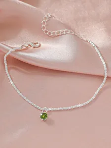 Silbernes Fusskettchen mit glitzernder Kette und gruenem Edelstein, eleganter Schmuck.