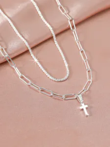 Silver layered necklace detail featuring sparkling chain and paperclip chain with cross.