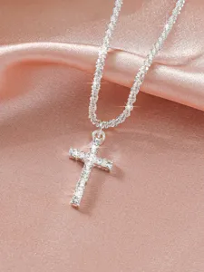 Detailed close-up of a sparkling rhinestone cross pendant necklace on silky pink satin.