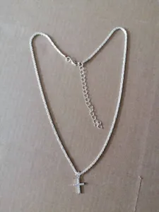 Silver color delicate clavicle chain necklace featuring a shiny cross pendant close-up view.